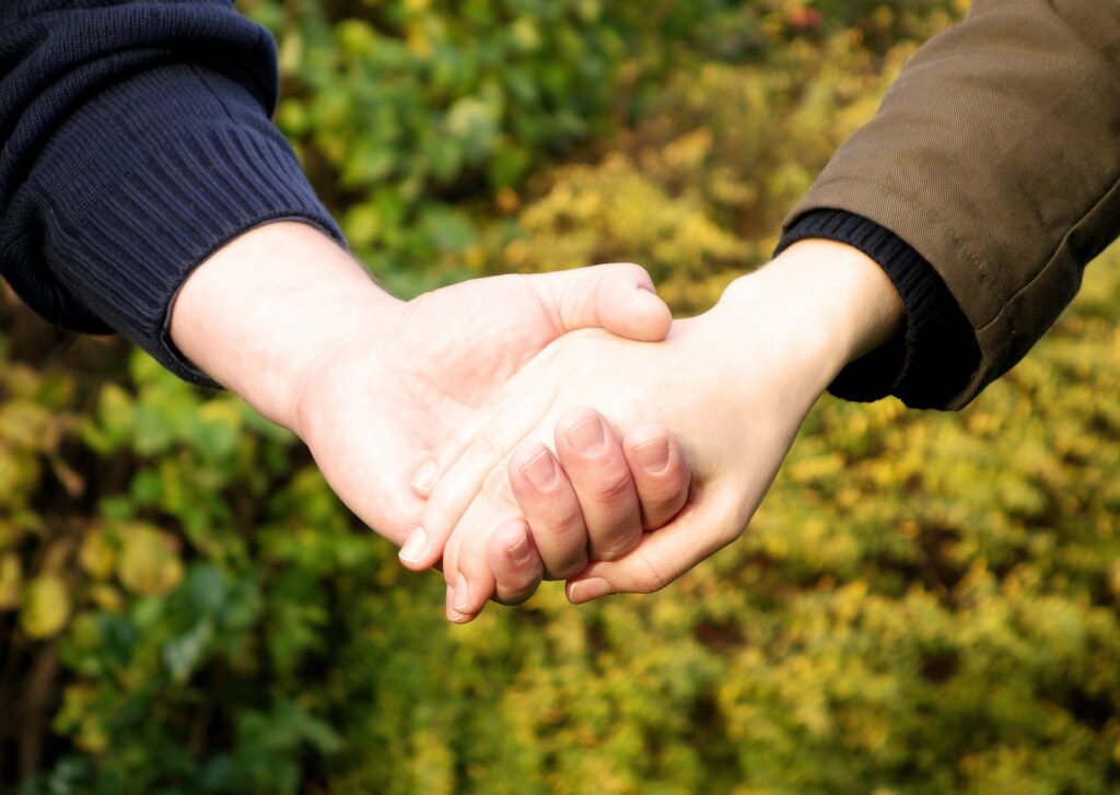 Twee personen houden elkaars handen vast
